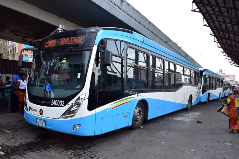 A blue and white BRT bus showing Oshodi to Obalende waits at the Obalende bus station in Lagos, with more buses lined up behind.