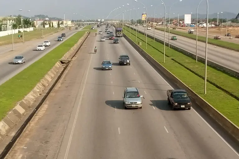 Cars travelling along the wide, tree-lined Kubwa Expressway in Abuja on a clear day.