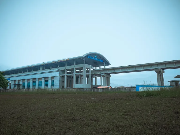 A Lagos Blue Line rail station with its curved blue roof beside the elevated track.