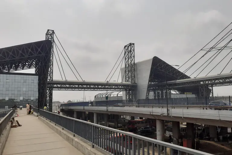 The Oshodi transport interchange in Lagos: cable-stayed steel frames and terminal buildings beside a pedestrian bridge.